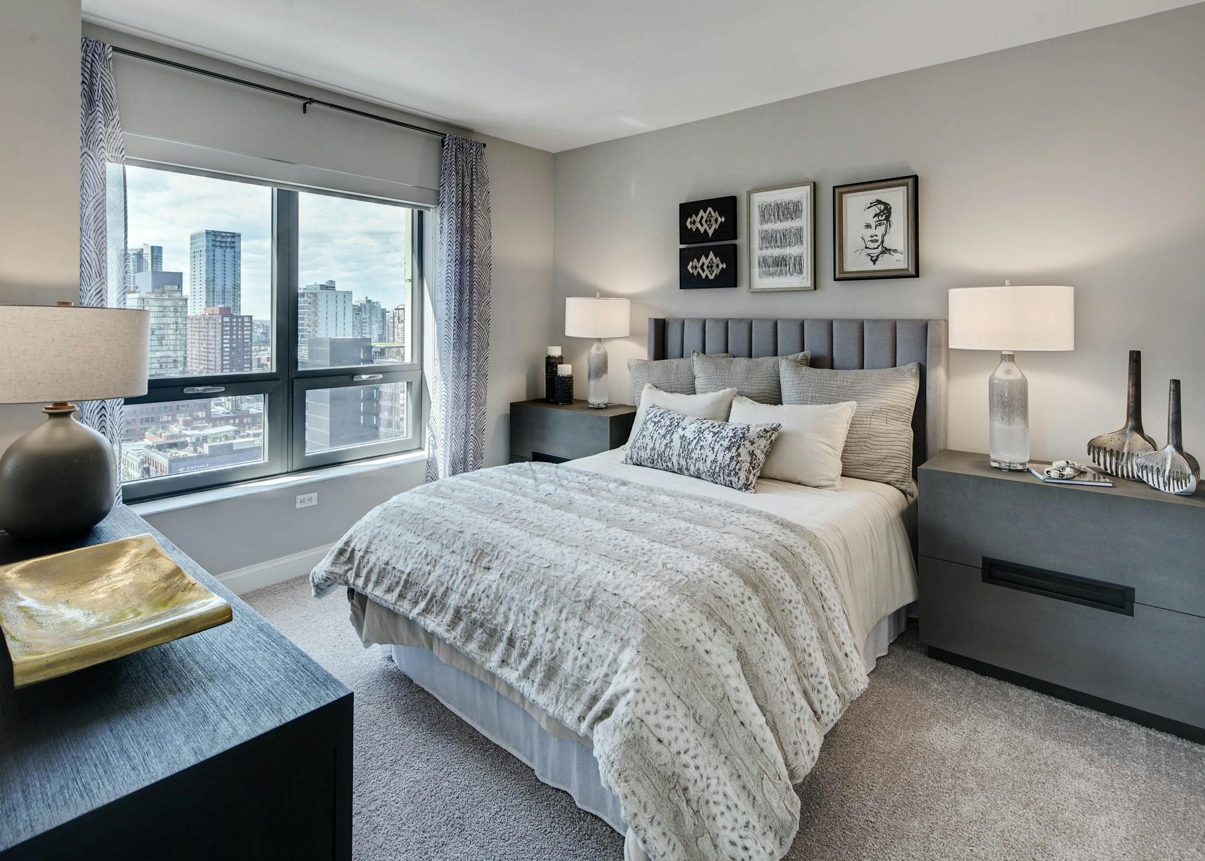 AMLI at River North apartment bedroom with grey furniture complimented by neutral bedding and carpeting with a bright window