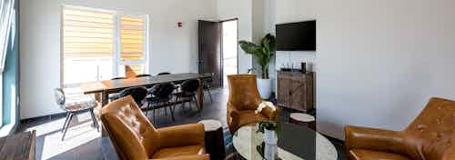 Interior daytime view of boater’s lounge with big screen TV, conference table and armchairs at AMLI Marina Del Rey apartments