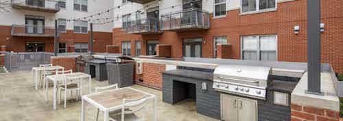 Grill area at AMLI Downtown apartments with two steel grills set in dark gray brick and white seating and hanging lights above