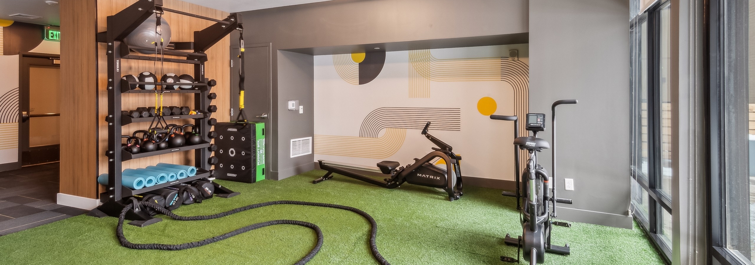 AMLI Broadway Park yoga studio with artificial green turf and a stationary bike as well as a variety of balls and weights