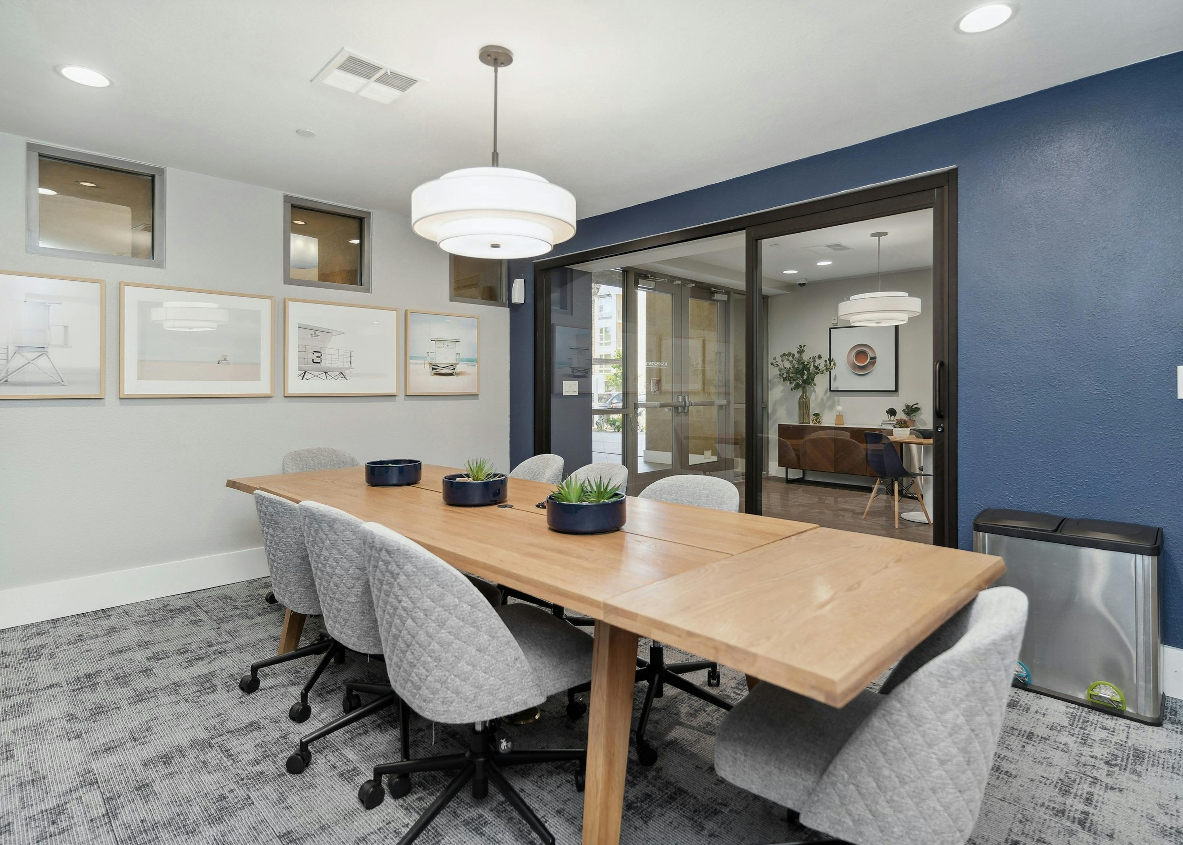 View of conference room wood table and gray office chairs with glass door facing the business center at AMLI Warner Center
