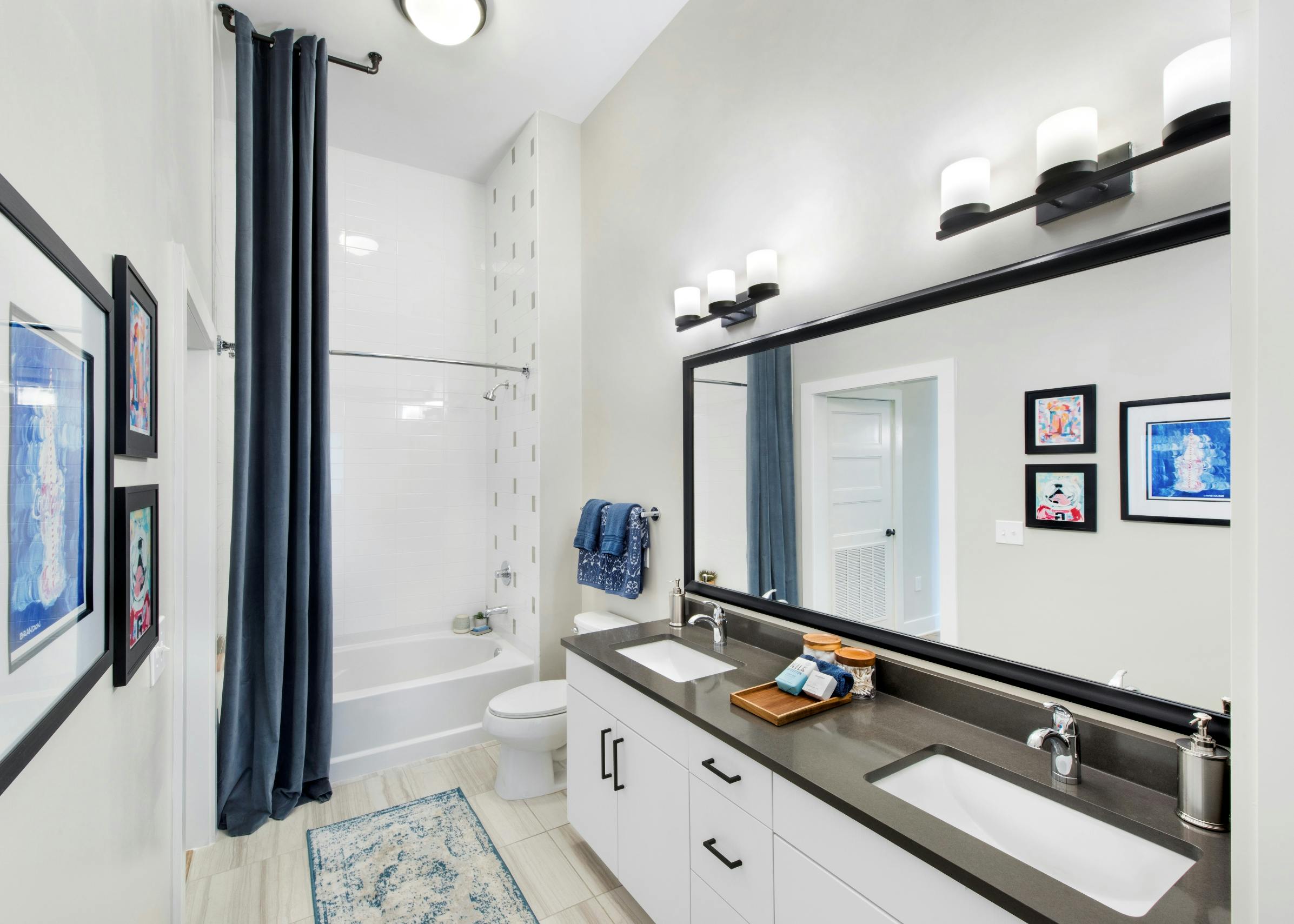 Interior view of AMLI Dectaur apartment bathroom with double vanity, soaking tub and framed mirror.