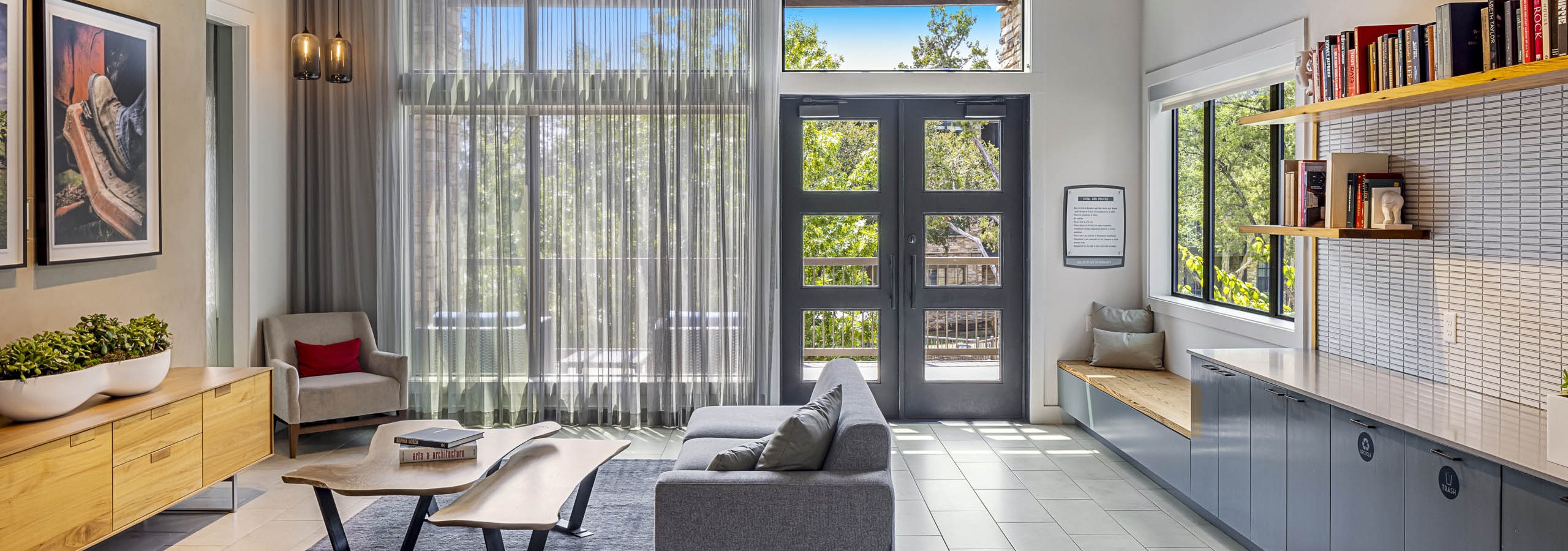 Clubhouse at AMLI Covered Bridge with window wall and couch and cabinets and shelves below modern chandelier