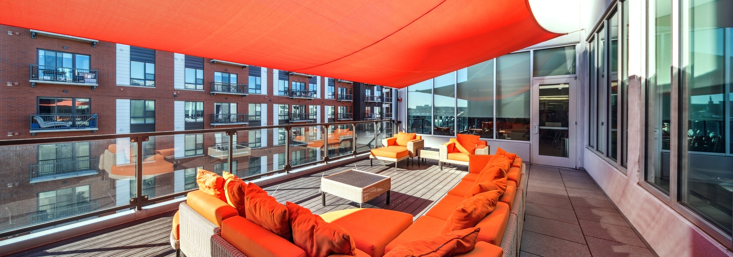 AMLI Denargo Market apartment building roof deck with orange couches and chairs and orange canopy and glass railing