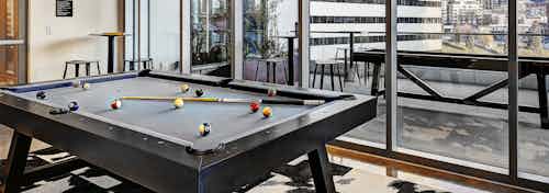 Interior club-room of AMLI Arc of pool-table and view of outdoor deck with shuffle board