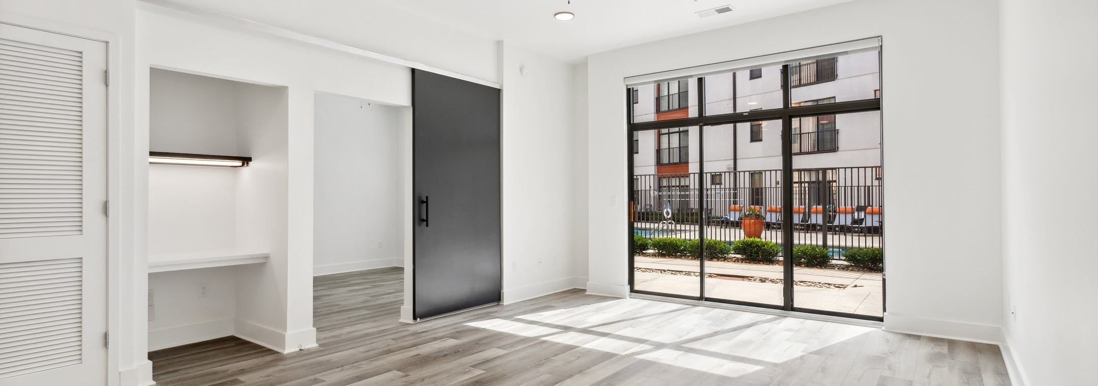 AMLI Old 4th Ward living room with gray wood flooring and office nook and bedroom sliding door and glass patio doors