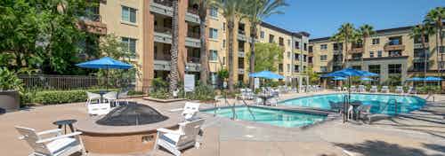AMLI Warner Center fire pit circled by four white chairs on pool deck and adjacent to heated spa and surrounded by building