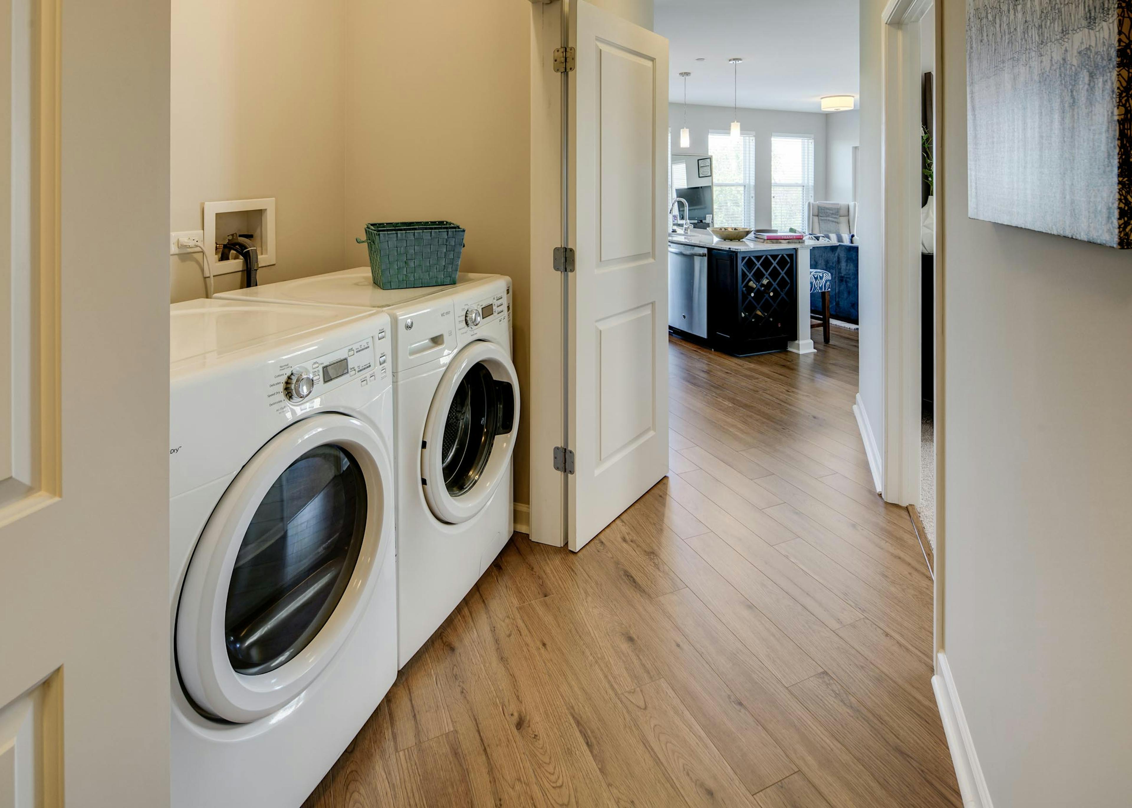 Close up of white closet doors opening up in AMLI Evanston apartment hallway to reveal sleek in unit laundry machines 