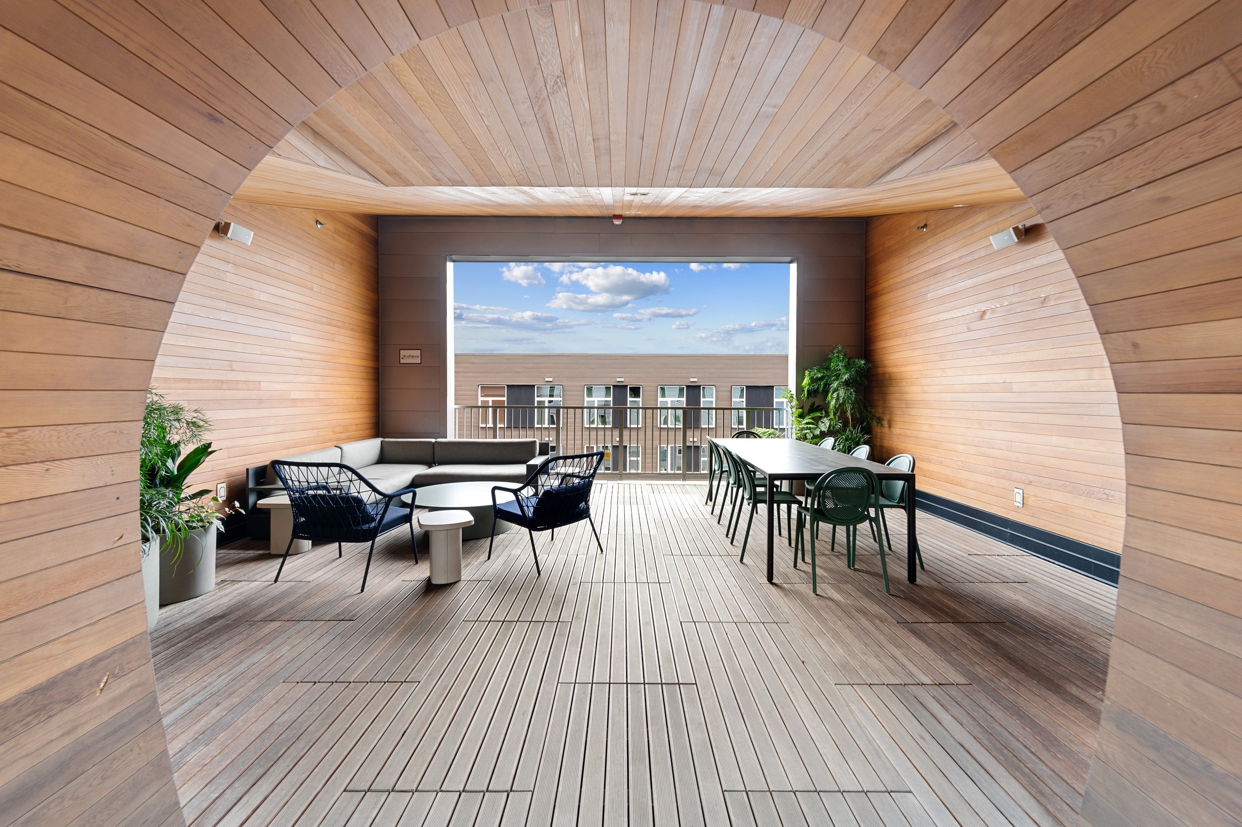 AMLI South Lake Union sky deck surrounded by wood paneling with tables and chairs and couch with view of a building and sky