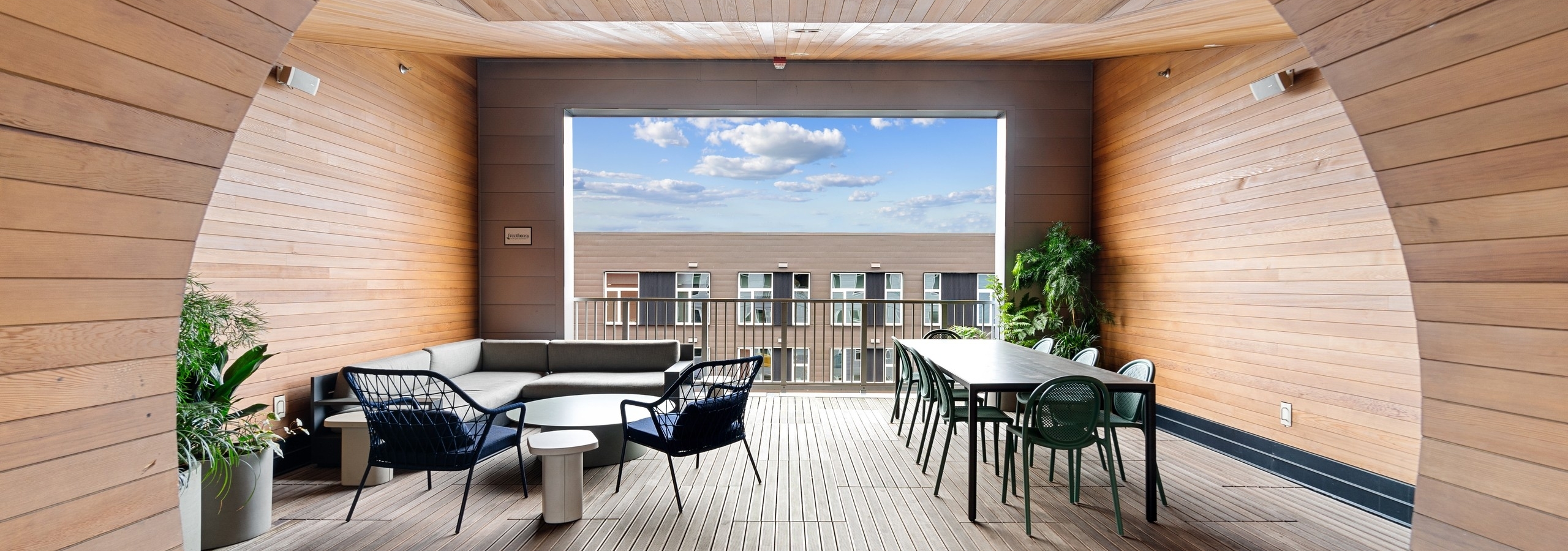 AMLI South Lake Union sky deck surrounded by wood paneling with tables and chairs and couch with view of a building and sky