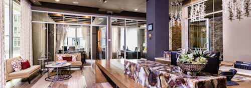 Interior daytime view of AMLI RidgeGate leasing office with 2 glass wall offices, stylish concierge desk and pendant lighting