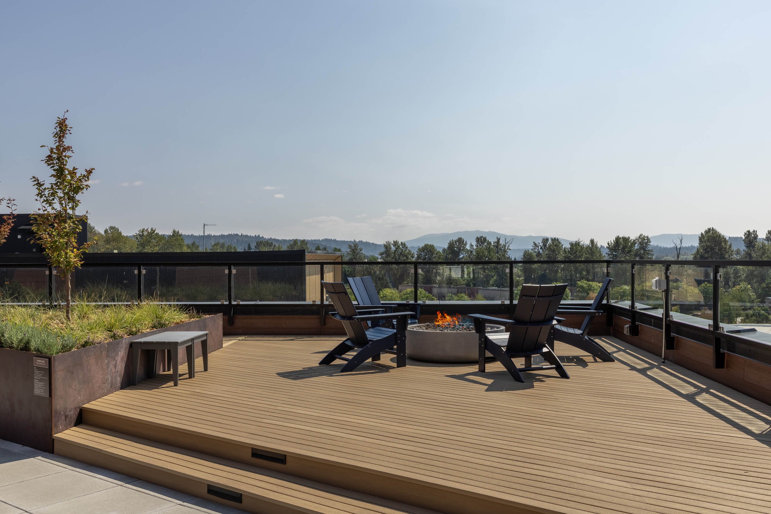 Perch rooftop deck with a lit fire pit, lounge chairs, and sweeping views of the surrounding hills and mountains.