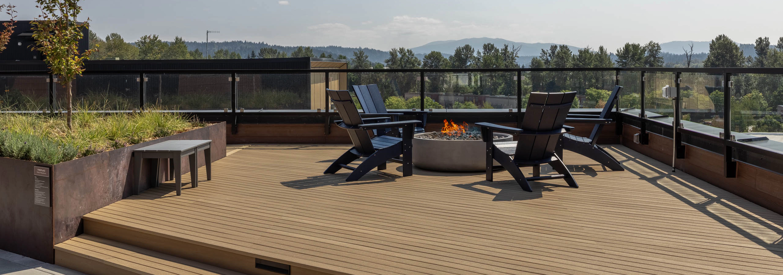 Perch rooftop deck with a lit fire pit, lounge chairs, and sweeping views of the surrounding hills and mountains.