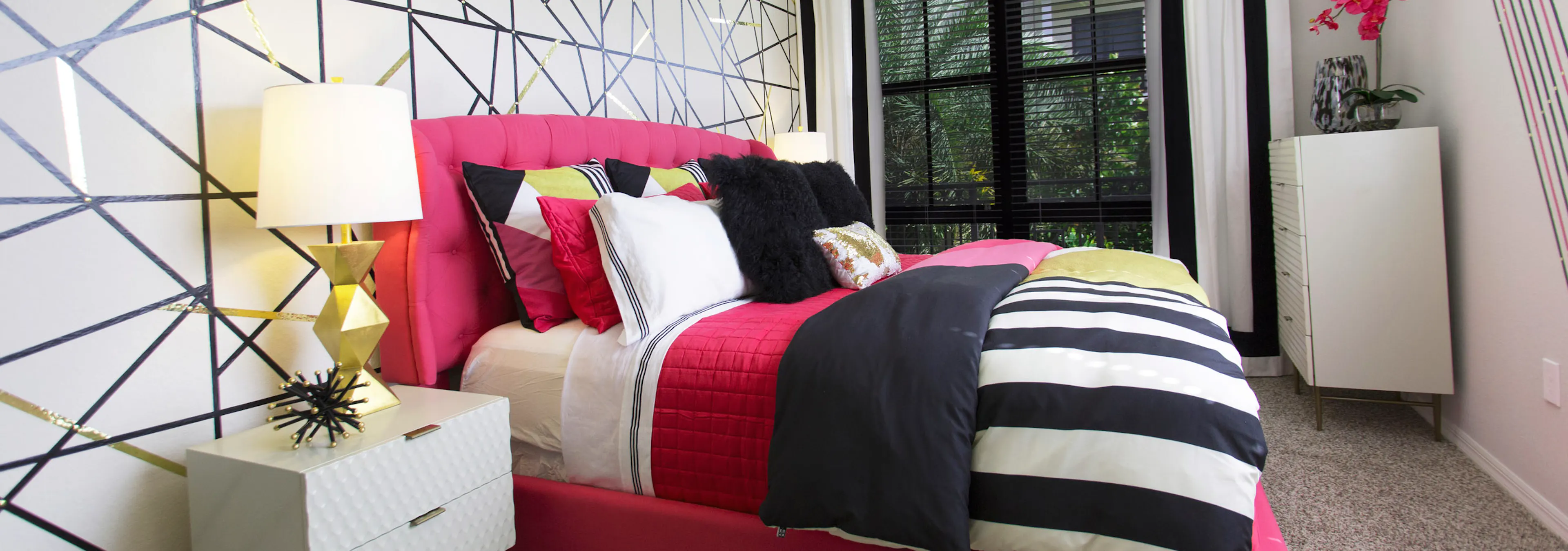 AMLI Dadeland bedroom with pink bed and black and white striped bedding.