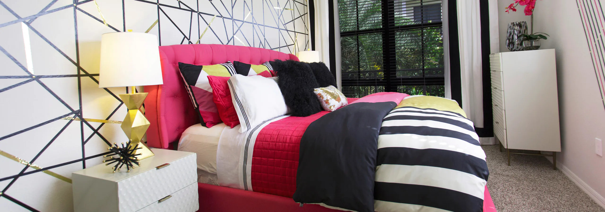 AMLI Dadeland bedroom with pink bed and black and white striped bedding.
