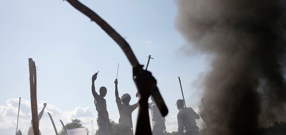 Des hommes font un geste devant une barricade brûlée lors d'une manifestation contre les soldats français à Bambari