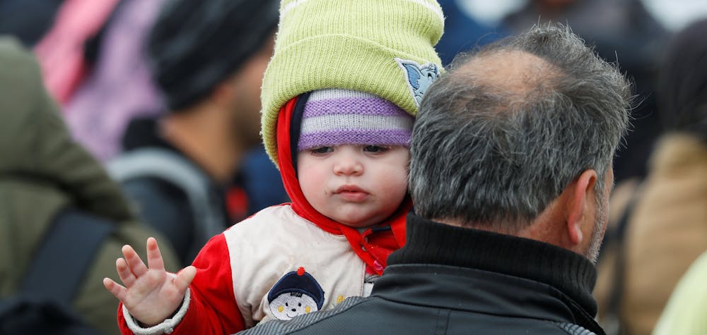 A migrant holding a child walks near the Turkey's Pazarkule border crossing with Greece's Kastanies, near Edirne, Turkey, March 4, 2020. 