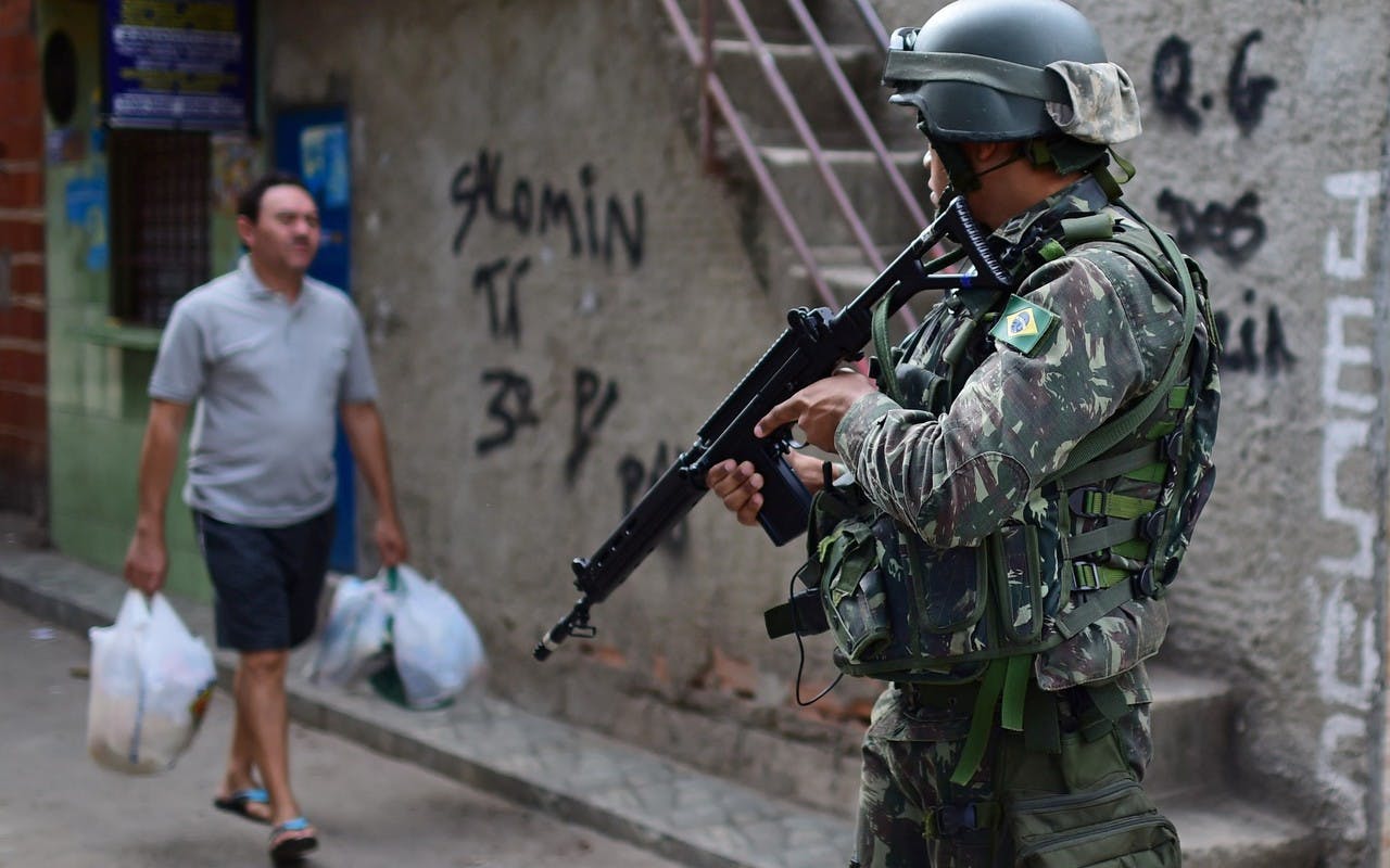 Brésil. Soldat avec armes et homme avec sacs de courses.