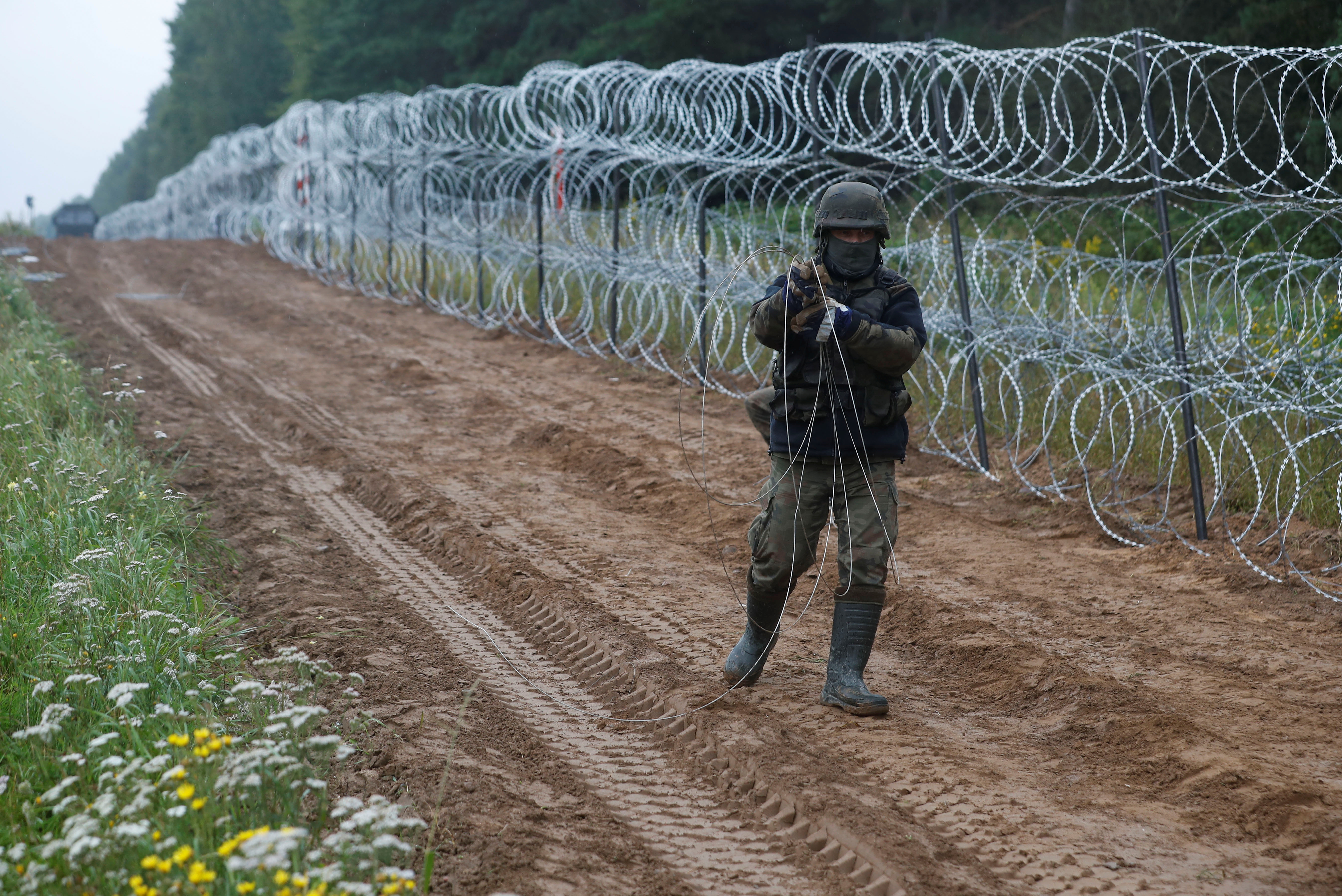 Un soldat polonais construit une clôture à la frontière entre la Pologne et le Bélarus près du village de Nomiki, en Pologne, le 26 août 2021. REUTERS/Kacper Pempel
