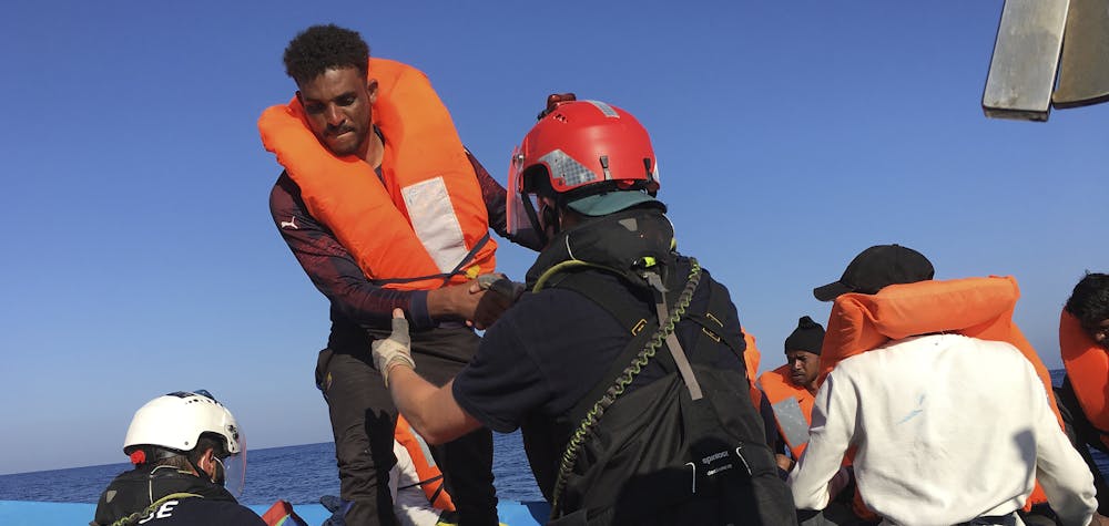 
L'un des 47 migrants secourus plus tôt aujourd'hui par des membres de l'ONG française SOS Méditerranée Ocean Viking à 55 km au large des côtes de l'île italienne de Lampedusa est aidé par des sauveteurs le 30 juin 2020. Quarante-sept migrants sur un bateau en bois ont été secourus le 30 juin , 2020 par des militants de l'Ocean Viking, affrétés par le groupe d'aide français SOS-Méditerranée, a déclaré un journaliste de l'AFP à bord.
