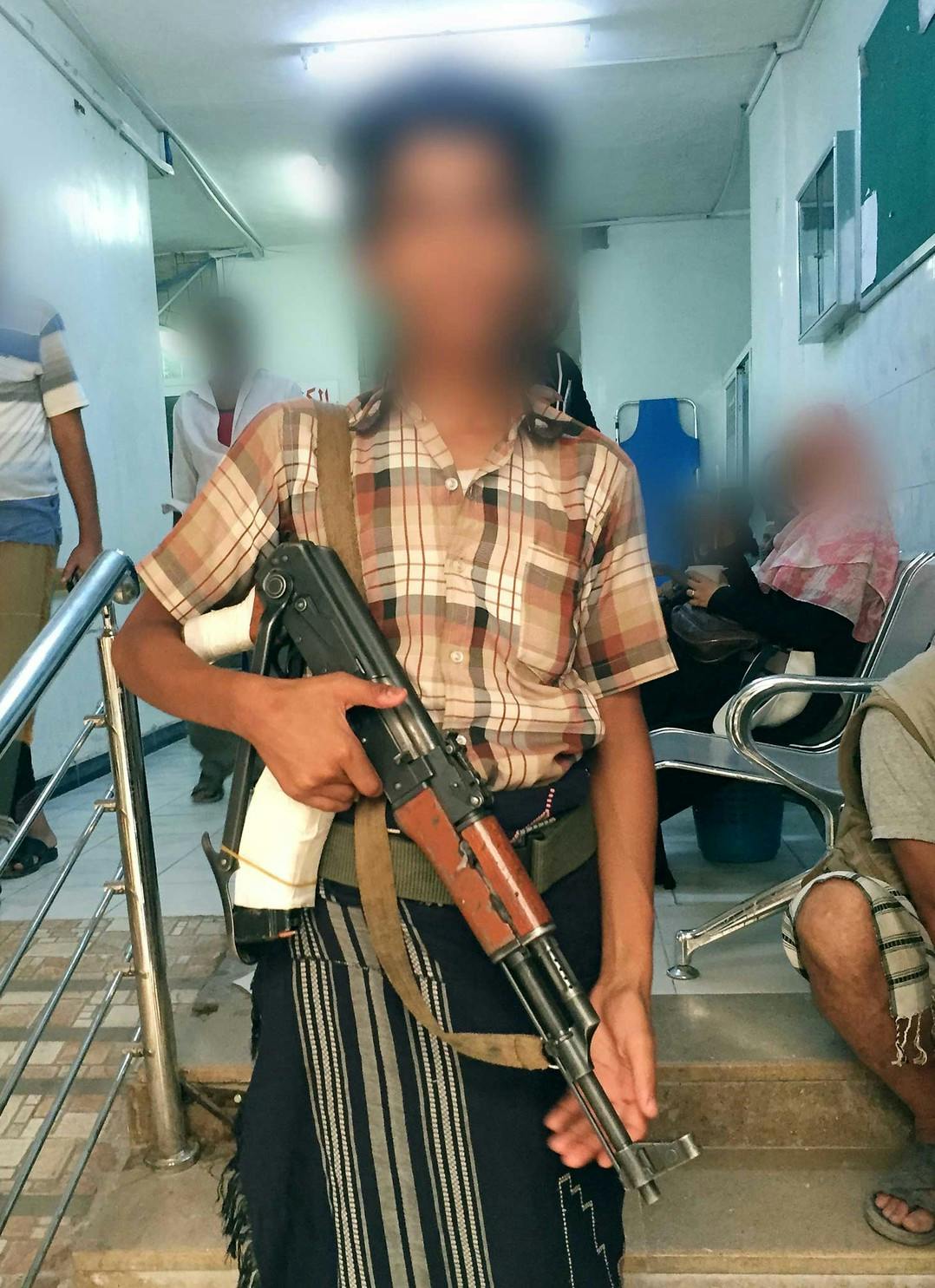 Enfant (âgé de 14-15 ans) portant un fusil d'assaut à l'hôpital al-Rawdha, mai 2015