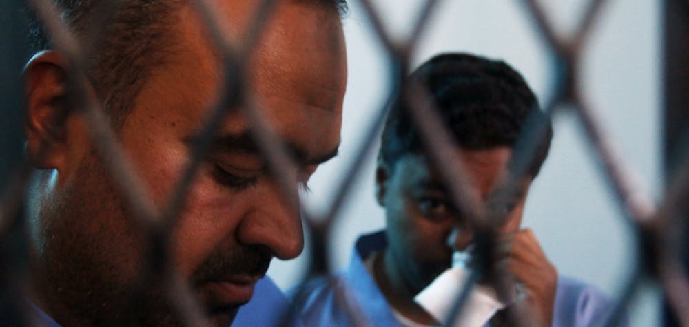 Defendants Abdulkarim Lalji (L) and Hani Ahmad Mohammad, convicted of spying for Iran, stand behind courtroom bars at a state security court of appeals in Sanaa March 25, 2013. The court on Monday commuted their death sentences to five years in prison. The pair were convicted in 2009 of providing the Iranian Embassy in Yemen with military information, according to the Yemen News Agency (SABA).  REUTERS/Khaled Abdullah 