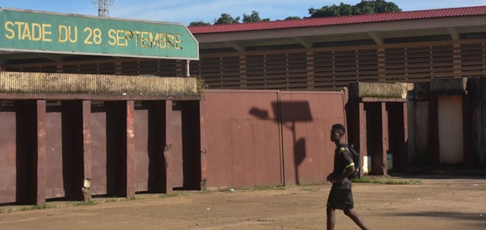  	A man walks past the entrance to the Stadium of the 28th September in Conakry on September 26, 2022 on the eve of the opening of the trial of eleven men accused of being responsible for the massacre of over 150 protesters at the same stadium in 2009. - Countless Guineans have waited 13 years for the trial of former junta leader Moussa Dadis Camara and others held responsible for an appalling massacre committed on September 28, 2009. That time has come. Victims and relatives will head on Wednesday to a brand-new court in Conakry, where the trial of Captain Camara and 10 former officials will open, barring a last-minute adjournment. (Photo by CELLOU BINANI / AFP) (Photo by CELLOU BINANI/AFP via Getty Images) 