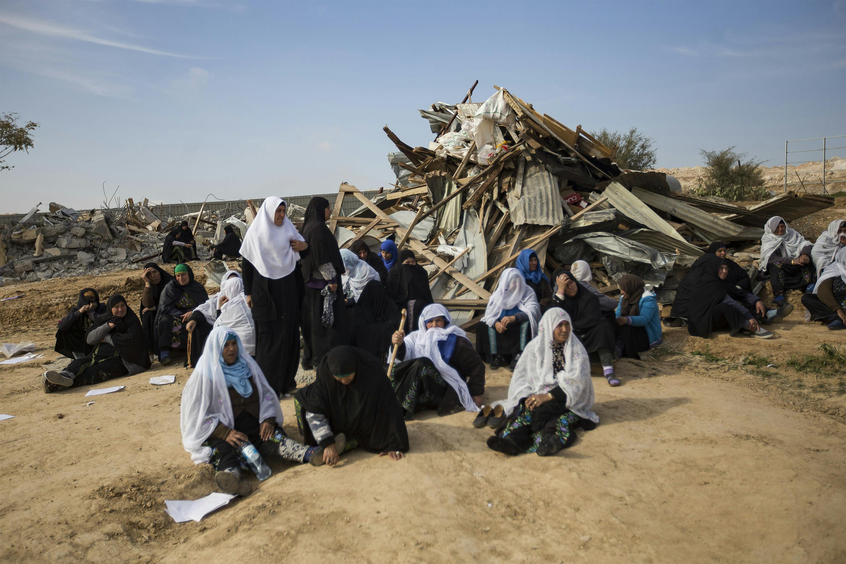  Bedouin women sit next to the ruins of their demolished houses in the unrecognized Bedouin village of Umm Al-Hiran, in the Negev desert, Israel, January 18, 2017. A resident and an Israeli policeman were killed during the operation. Israeli authorities said the policeman was killed in a car-ramming attack, while residences and activists claimed the driver was first shot dead by the police, with no apparent reason, before losing control of his car and driving towards the policemen.&nbsp;The Israeli state plans to completely demolish the village in order to build a Jewish-only town on that land. Faiz Abu Rmeleh