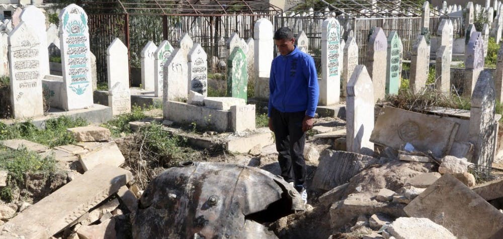 Un homme regarde une bombe baril larguée par les forces syriennes sur le cimetière du quartier d'al-Qatanah, Alep