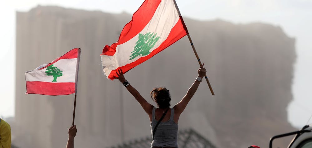 Demonstrators wave Lebanese flags during protests near the site of a blast at Beirut's port area, Lebanon August 11, 2020. 