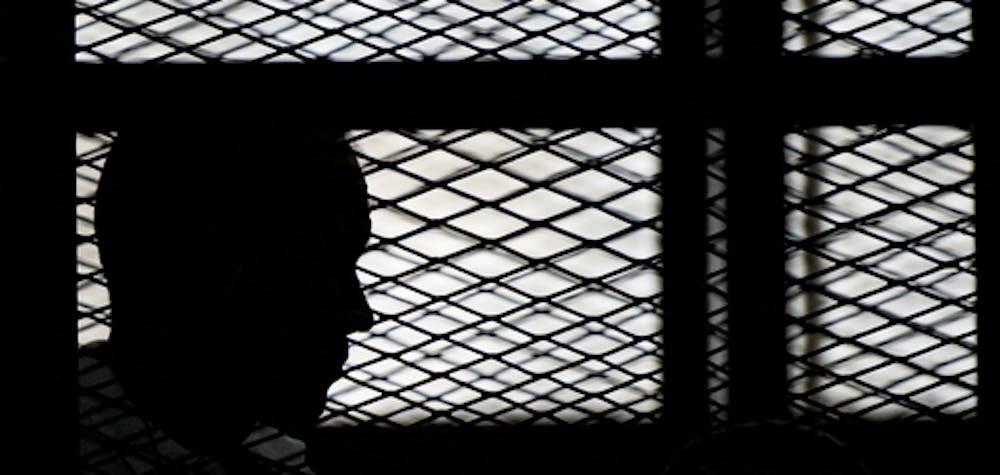 Al-Jazeera channel's Australian journalist Peter Greste stands inside the defendants cage during his trial for allegedly supporting the Muslim Brotherhood on June 1, 2014 at the police institute near Cairo's Tora prison. The high-profile case that sparked a global outcry over muzzling of the press is seen as a test of the military-installed government's tolerance of independent media, with activists fearing a return to autocracy three years after the Arab Spring uprising that toppled Hosni Mubarak. AFP PHOTO / KHALED DESOUKI (Photo credit should read KHALED DESOUKI/AFP via Getty Images)
