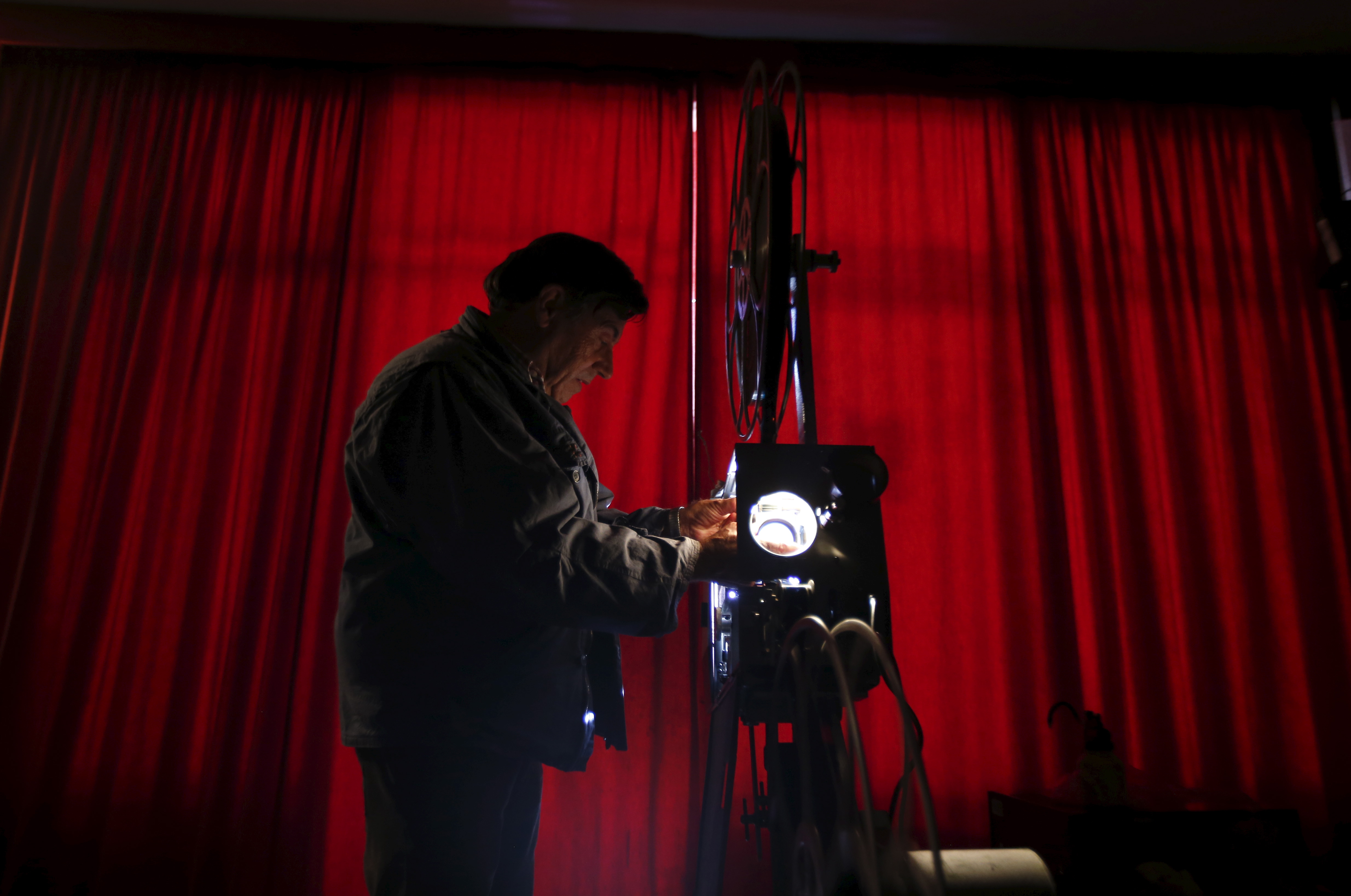 Projectionist Antonio Feliciano, 75, checks his projector before showing a film in Monforte, Portugal May 16, 2015.  Shades of Oscar-winning classic "Cinema Paradiso" run through the life of Feliciano, a sprightly 75-year-old who fears he may be the last of Portugal's travelling film projectionists.After six decades travelling four million km (2.5 million miles) to screen 4,000 films in Portugal's far-flung villages, Feliciano does not plan to retire just yet. But he is resigned to the fact that the Internet, digital TV and distribution monopolies have made his craft obsolete. Picture taken May 16, 2015. REUTERS/Rafael Marchante    