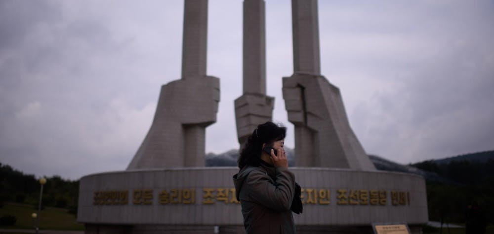 Une femme avec son téléphone portable devant le monument du Parti à Pyongyang 2015