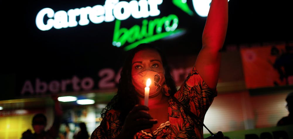 A woman holds a candle during a protest in front of a Carrefour supermarket in Brasilia, Brazil, after Joao Alberto Silveira Freitas was beaten to death by security guards at a Carrefour supermarket in Porto Alegre, November 26, 2020. 