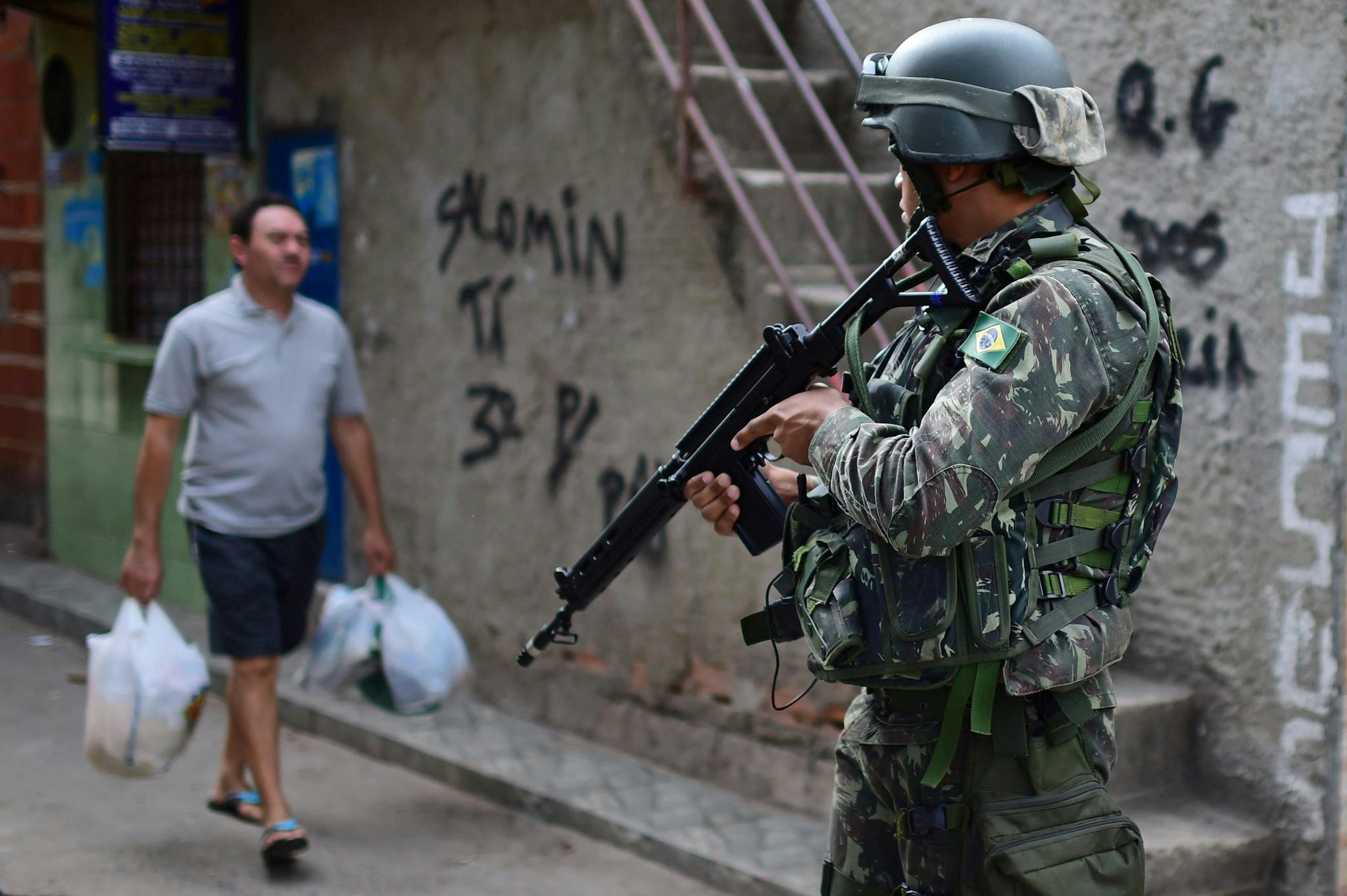 Brésil. Soldat avec armes et homme avec sacs de courses.