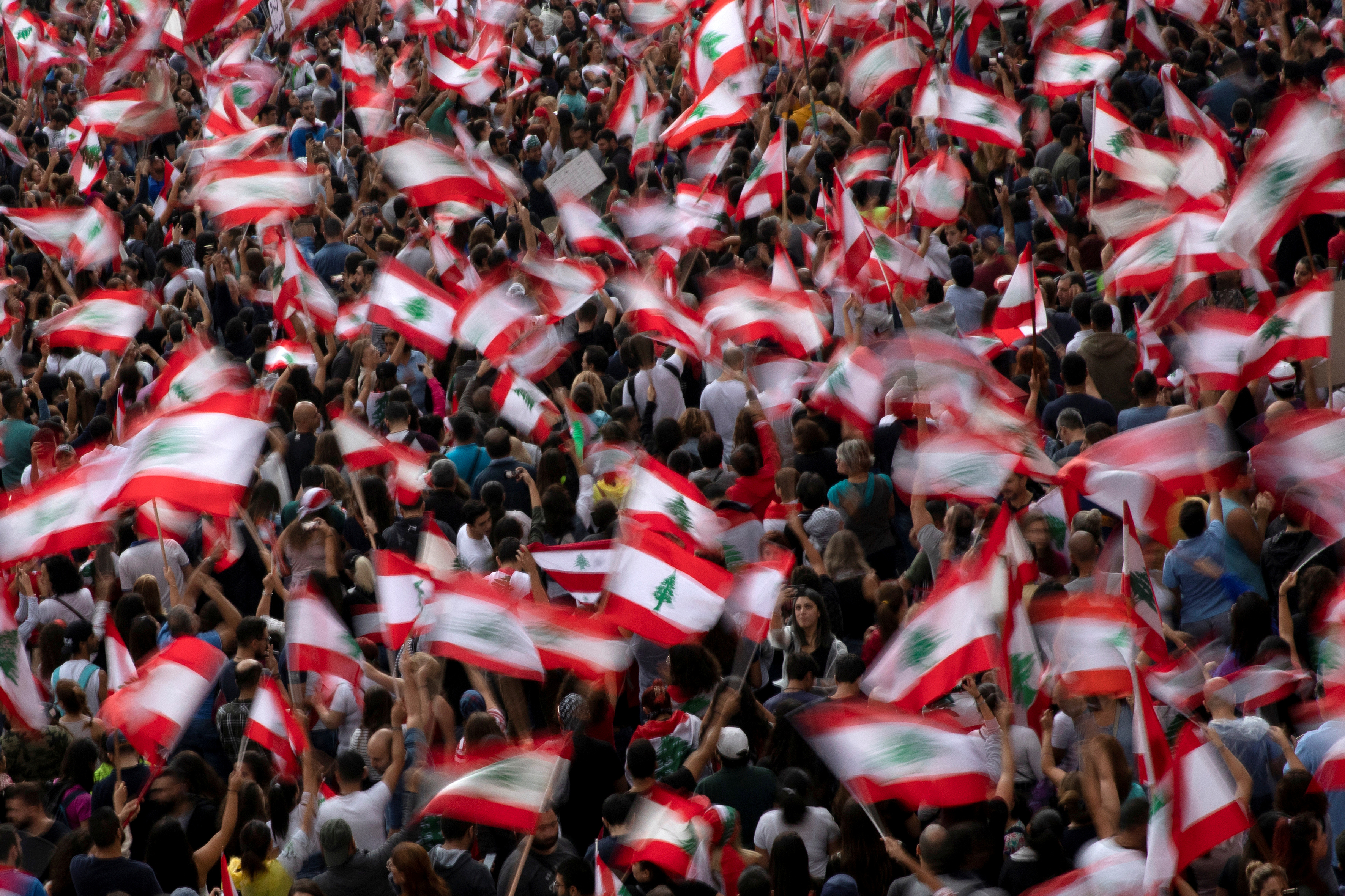 Demonstrators wave Lebanese national flags during ongoing anti-government protests at a highway in Jal el-Dib, Lebanon, October 23, 2019. 
