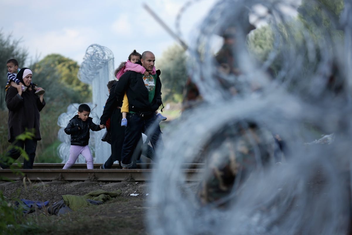 Hungary - Migrants walk through razor wire fencing