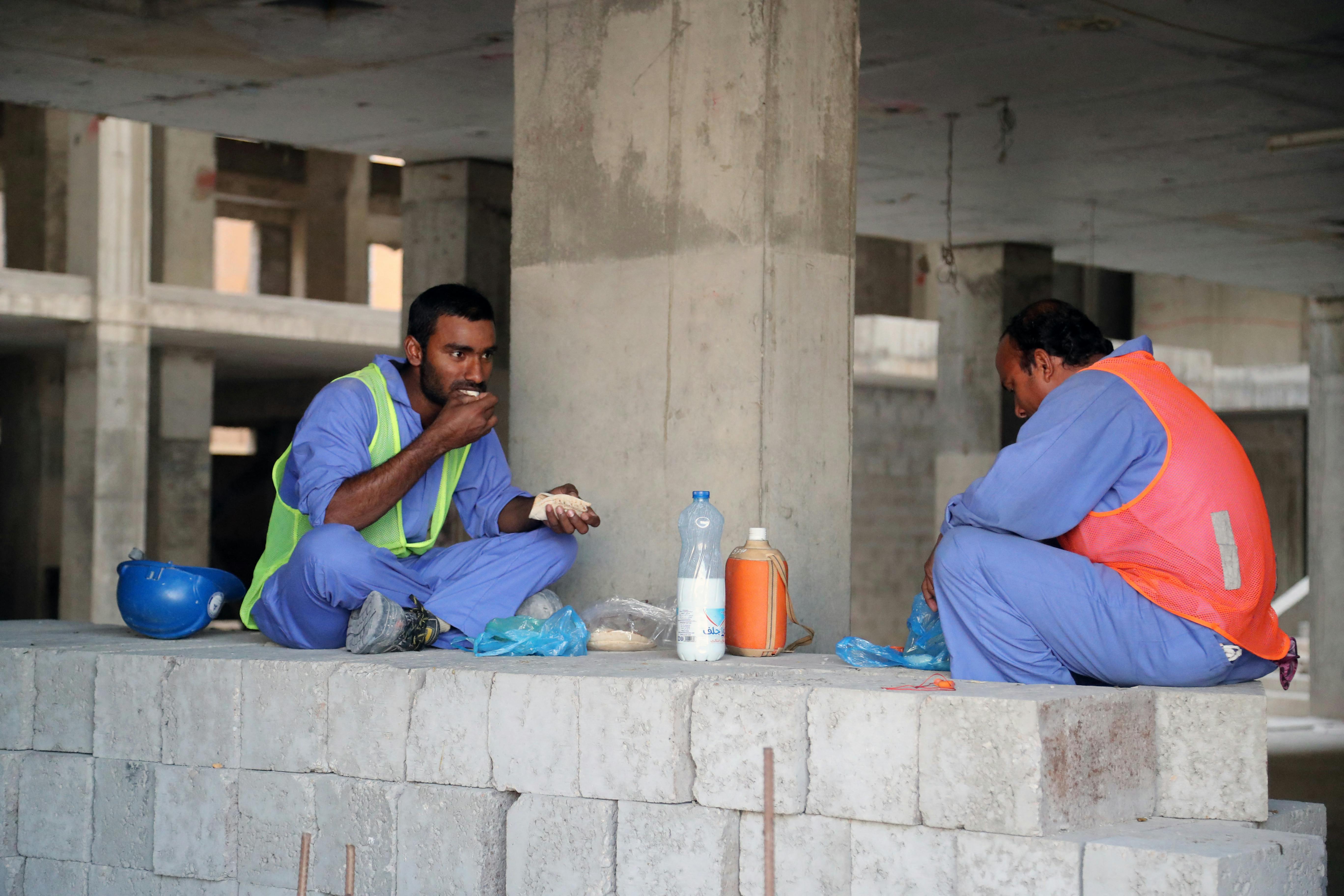 Migrant workers eat during a break at a construction site in the Qatari capital Doha on December 6, 2016. - Ever since being chosen as the 2022 World Cup host, Qatar's labour laws have been internationally condemned and kafala has been at the heart of that criticism. (Photo by STRINGER / AFP) / Qatar OUT / QATAR OUT