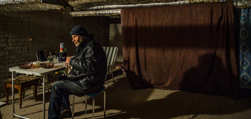 Un vieil homme déjeune à l'intérieur d'un abri dans le sous-sol de sa maison dans le nord de Kharkov, en Ukraine