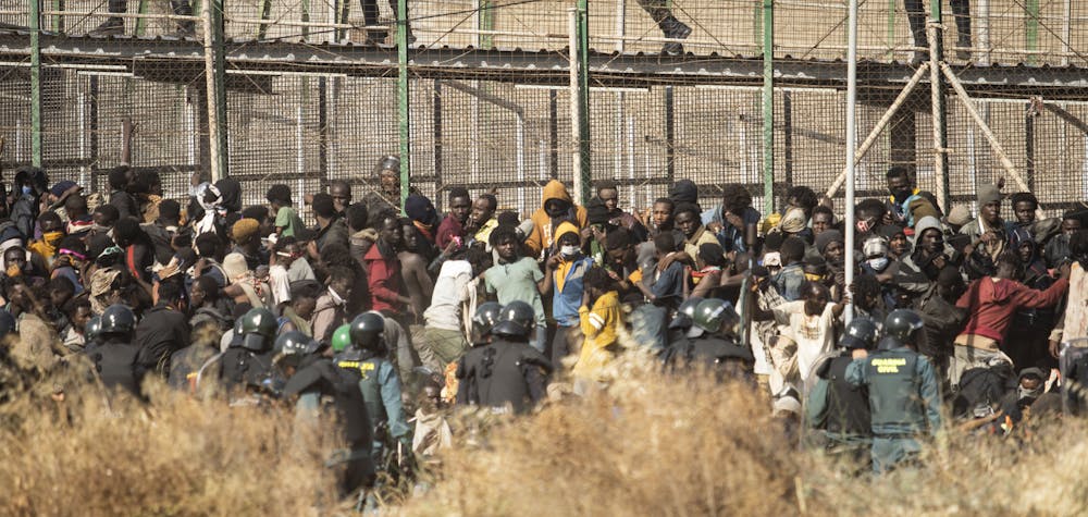 Des policiers anti-émeutes bouclent la zone après l'arrivée de personnes migrantes et réfugiées sur le sol espagnol et le franchissement des clôtures séparant l'enclave espagnole de Melilla du Maroc à Melilla, en Espagne, le 24 juin 2022.