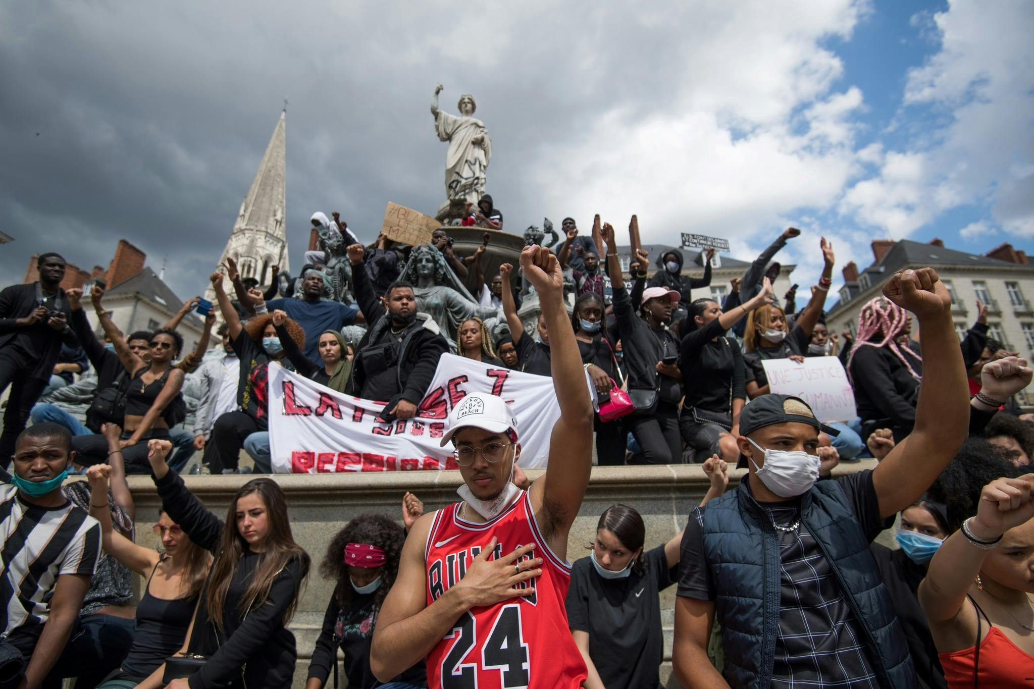 Des personnes portant des masques de protection scandent des slogans, lèvent le poing et tiennent des pancartes, alors qu'elles manifestent à Nantes, le 8 juin 2020, lors d'une manifestation mondiale "Black Lives Matter" contre le racisme et la brutalité policière à la suite de la mort de George Floyd, un homme noir non armé tué lors de son arrestation par la police à Minneapolis.