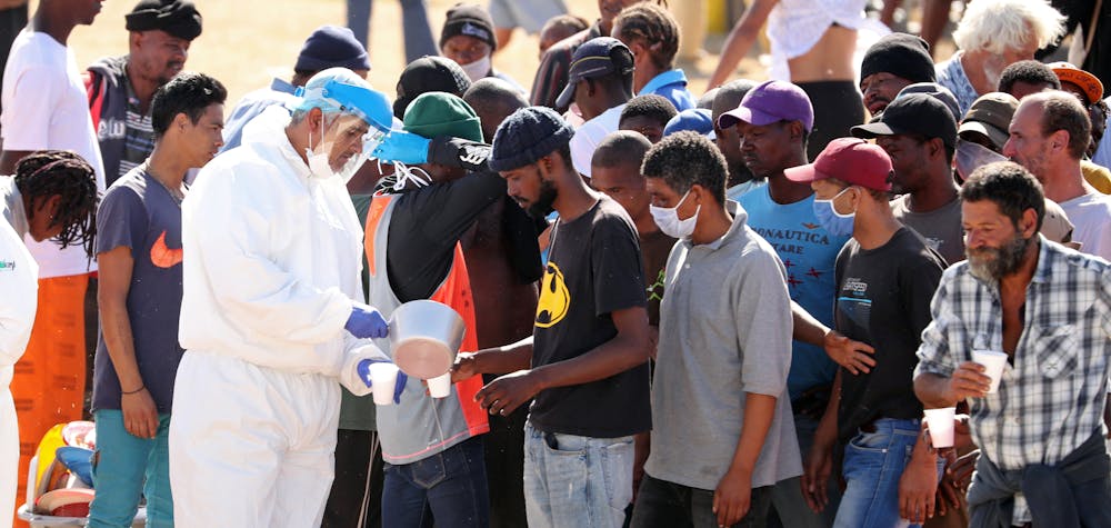 Homeless people queue for food at a camp set up by disaster management authorities during the 21-day nationwide lockdown aimed at limiting the spread of coronavirus disease (COVID-19) in Cape Town, South Africa, April 9, 2020. 