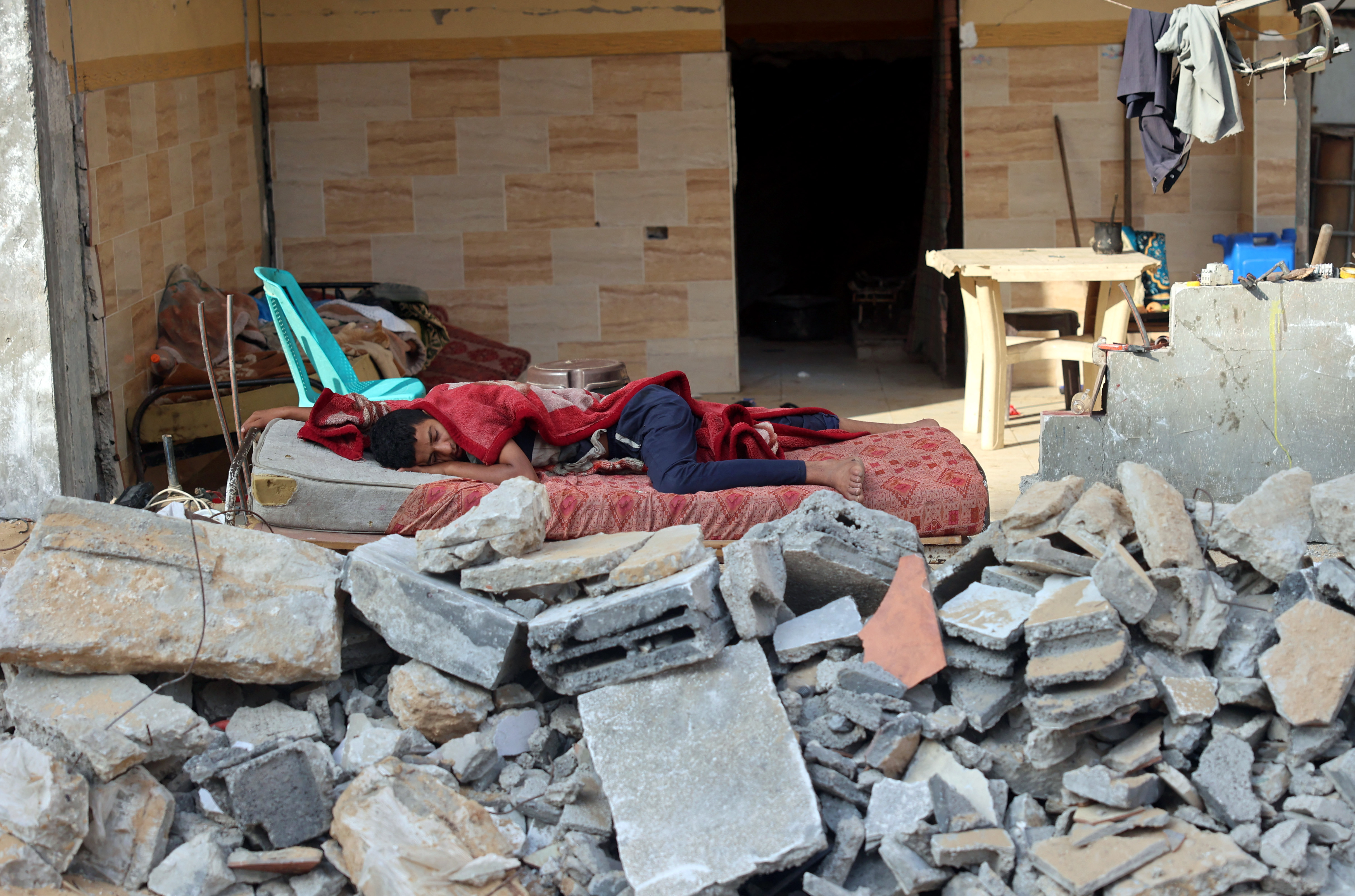 A Palestinian boy sleeps in the ruins of his family house that was destroyed in Israeli air strikes during the most recent Israeli-Palestinian fighting, in Gaza City, on July 2, 2021. (Photo by MOHAMMED ABED / AFP)