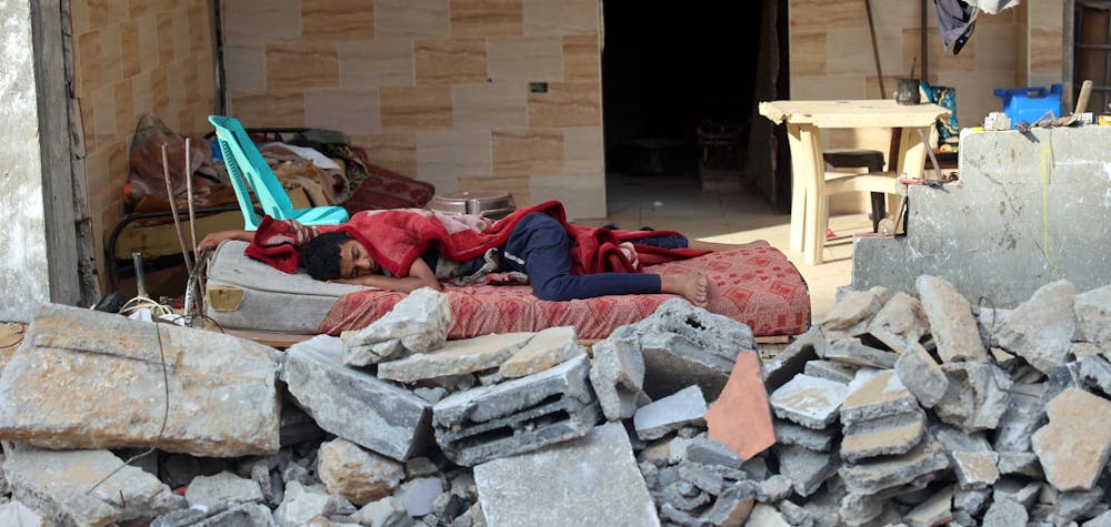 A Palestinian boy sleeps in the ruins of his family house that was destroyed in Israeli air strikes during the most recent Israeli-Palestinian fighting, in Gaza City, on July 2, 2021. (Photo by MOHAMMED ABED / AFP)