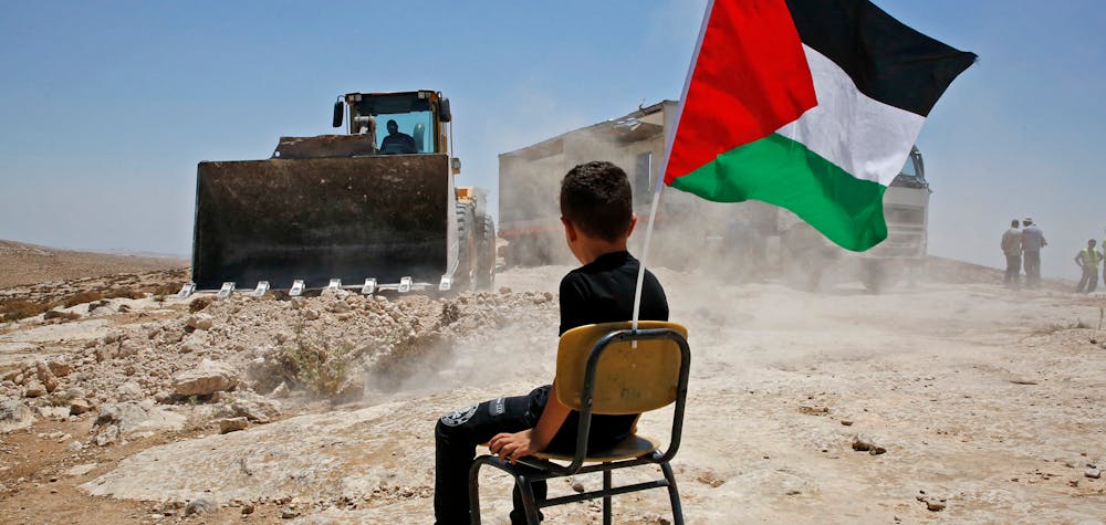  Un garçon palestinien est assis sur une chaise avec un drapeau national alors que les autorités israéliennes démolissent le site d'une école dans le village de Yatta, au sud de la ville d'Hébron en Cisjordanie, et pour être relocalisé dans une autre zone, le 11 juillet 2018.