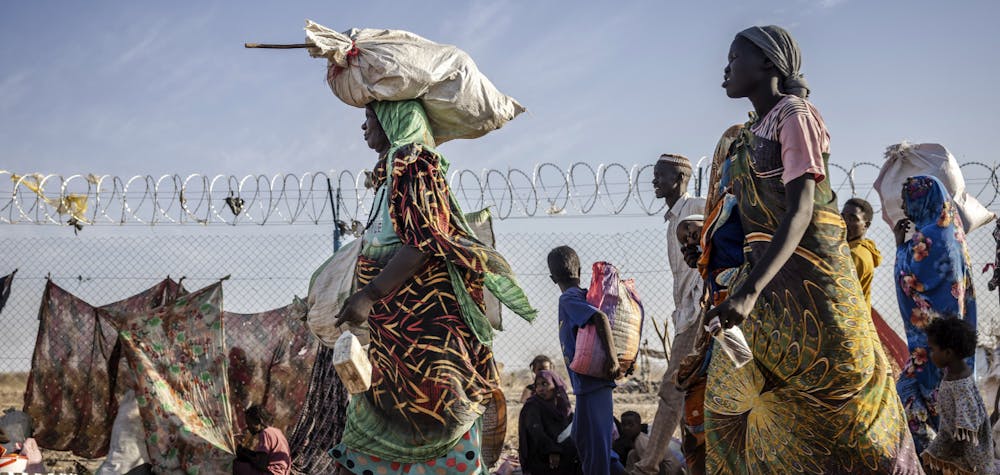Des réfugié·es soudanais·es et des rapatrié·es sud-soudanais·es qui ont fui la guerre au Soudan portent leurs effets personnels à leur arrivée dans un centre de transit pour réfugiés à Renk, le 14 février 2024.  © LUIS TATO / AFP