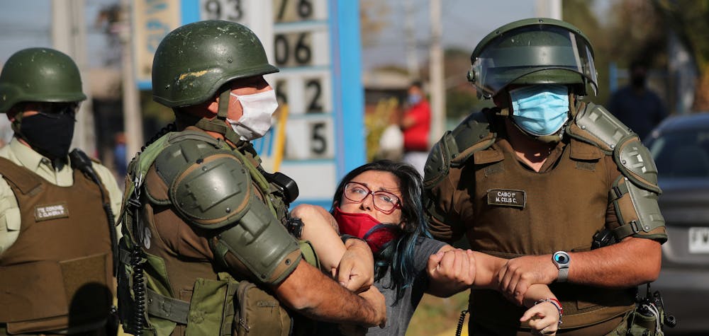 A woman is detained after shouting slogans against riot police at a poor neighborhood where people are protesting the lack of help from the government, during a general quarantine imposed due to a surge of fresh coronavirus disease (COVID-19) cases, at 'El Bosque' area in Santiago, Chile May 18, 2020. REUTERS/Ivan Alvarado