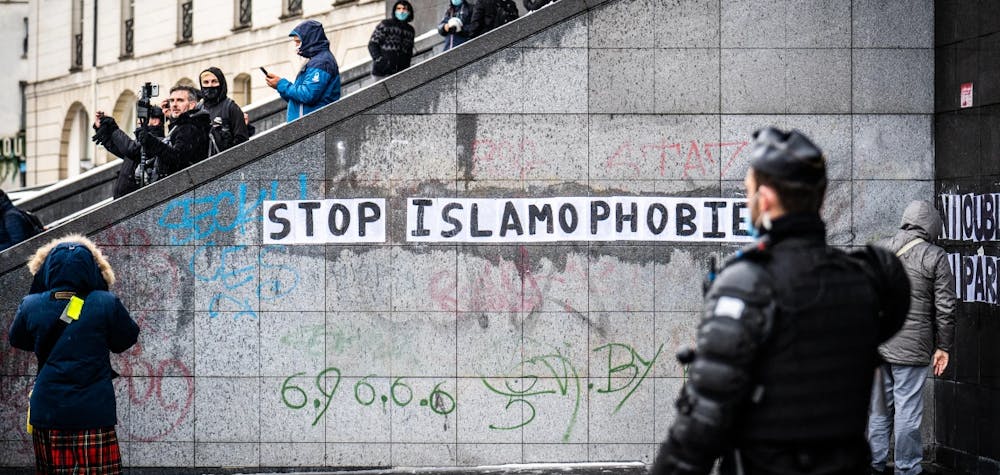Un gendarme passe devant un collage avec le message "stop islamophobie" sur la place de la Bastille