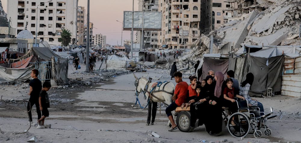 Des personnes circulent en charrette tirée par des chevaux devant des bâtiments détruits le long de la rue Al-Rasheed, dans l'ouest de la ville de Gaza, le 7 octobre 2025