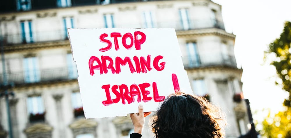 Une manifestante tient une pancarte avec le slogan "Stop arming Israël" (Arrêtez d'armer Israël) lors d'un rassemblement place de République à Paris en soutien au peuple palestinien de Gaza.